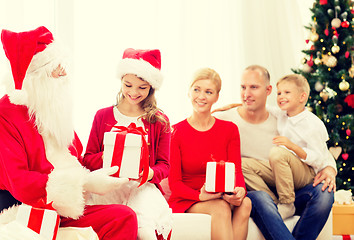 Image showing smiling family with santa claus and gifts at home