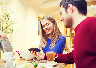 Image showing smiling couple with smartphones meeting at cafe