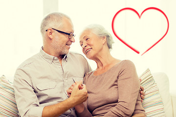 Image showing happy senior couple hugging on sofa at home