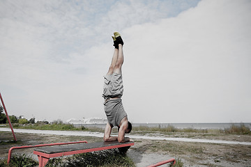 Image showing young man exercising on bench outdoors