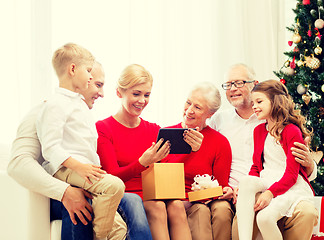 Image showing smiling family with tablet pc and gift box at home