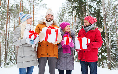 Image showing happy friends with gifts in snowy winter forest