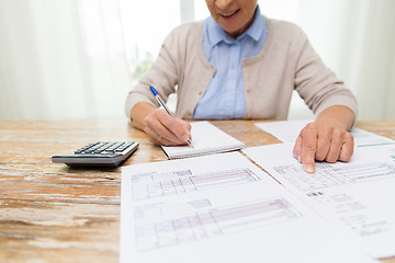 Image showing senior woman with papers and calculator at home