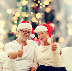 Image showing happy senior couple in santa helper hats