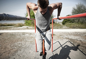 Image showing young man exercising on parallel bars outdoors