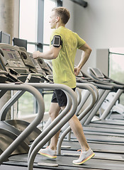 Image showing man with smartphone exercising on treadmill in gym