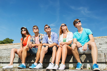 Image showing group of smiling friends sitting on city street