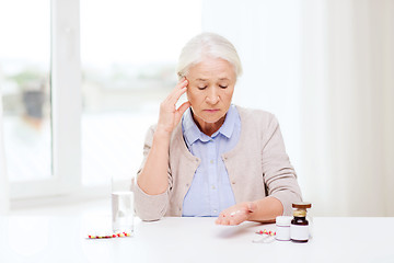 Image showing senior woman with water and medicine at home