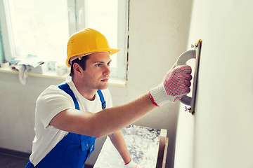 Image showing smiling builder with grinding tool indoors