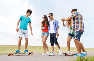 Image showing happy teenage friends with longboards outdoors