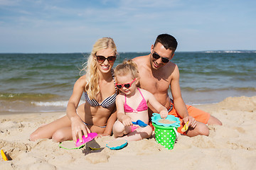 Image showing happy family playing with sand toys on beach