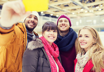 Image showing happy friends with smartphone on skating rink