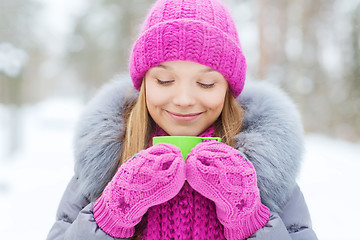 Image showing smiling young woman with cup in winter forest