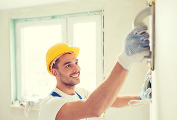 Image showing smiling builder working with grinding tool indoors