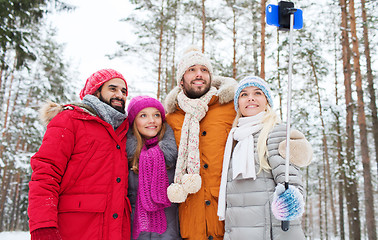 Image showing smiling friends with smartphone in winter forest