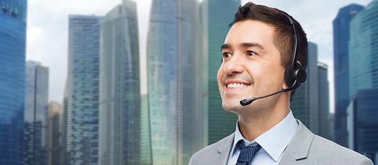 Image showing happy businessman in headset over city background