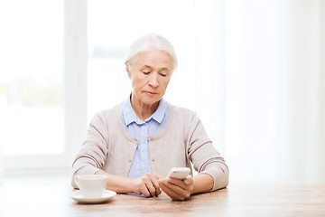 Image showing senior woman with smartphone texting at home