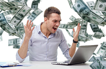 Image showing angry businessman with laptop and falling money