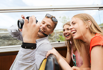 Image showing happy friends with camera traveling by tour bus