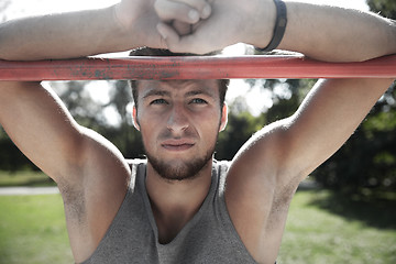 Image showing young man exercising on horizontal bar outdoors