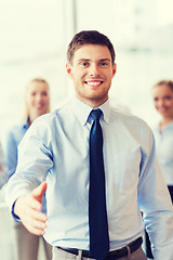 Image showing smiling businessman making handshake in office