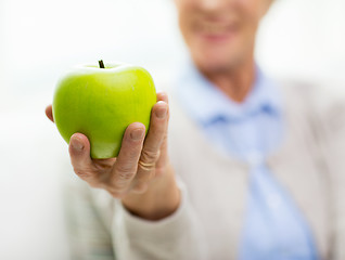 Image showing close up of senior woman hand holding green apple