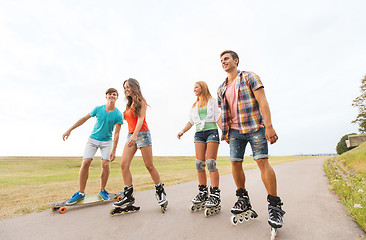 Image showing happy teenagers with rollerblades and longboards