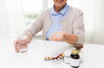 Image showing happy senior woman with water and pills at home