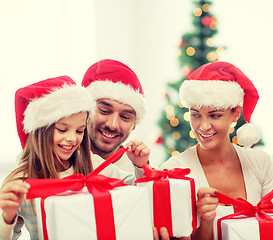 Image showing happy family in santa hats sitting with gift boxes