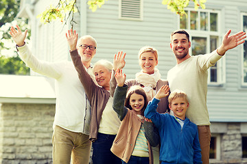 Image showing happy family waving hands in front of house