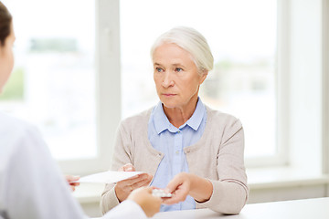 Image showing doctor giving prescription and drug to woman 