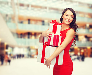 Image showing smiling woman in red dress with gift boxes