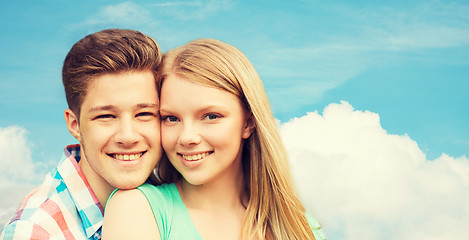 Image showing smiling couple hugging over blue sky background