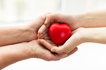 Image showing senior and young woman hands holding red heart