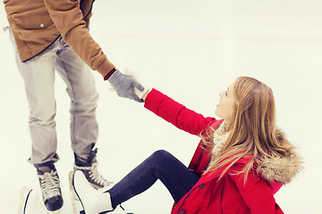 Image showing man helping women to rise up on skating rink