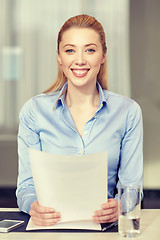 Image showing smiling woman holding papers in office