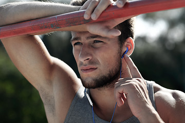 Image showing young man with earphones and horizontal bar