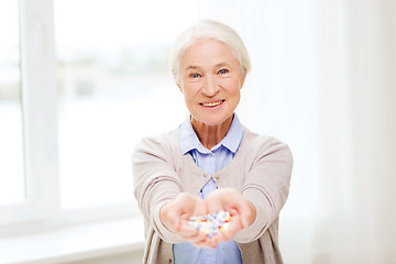 Image showing happy senior woman with medicine at home