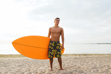 Image showing smiling young man with surfboard on beach