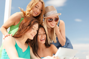 Image showing smiling girls looking at tablet pc in cafe