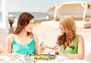 Image showing smiling girls in cafe on the beach