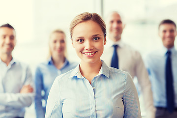 Image showing smiling businesswoman with colleagues in office