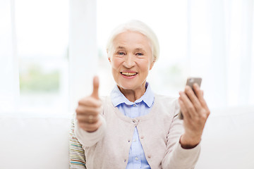 Image showing senior woman with smartphone showing thumbs up