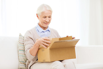 Image showing happy senior woman with parcel box at home