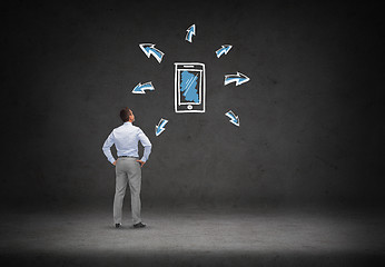 Image showing businessman looking smartphone over concrete wall