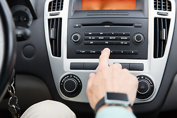 Image showing close up of male hand turning on radio in car