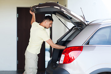 Image showing young man with open car trunk at parking space