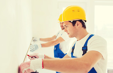 Image showing group of builders with measuring tape indoors