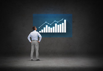 Image showing businessman looking at chart over concrete room