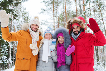 Image showing group of friends waving hands in winter forest